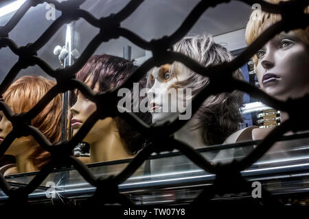 Parrucche visualizzato sul manichino teste in una vetrina di notte a Poznan, Polonia Foto Stock