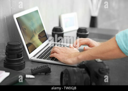 Fotografo a lavorare con il computer portatile in ufficio Foto Stock