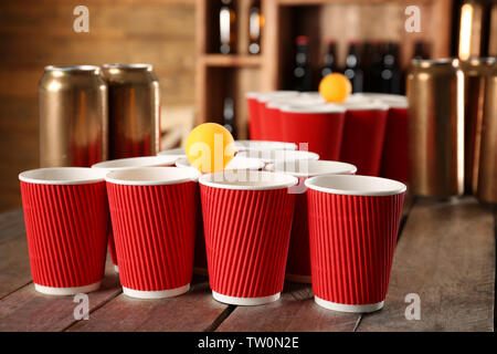 Birra in plastica pong tazze e la sfera sul tavolo di legno Foto Stock