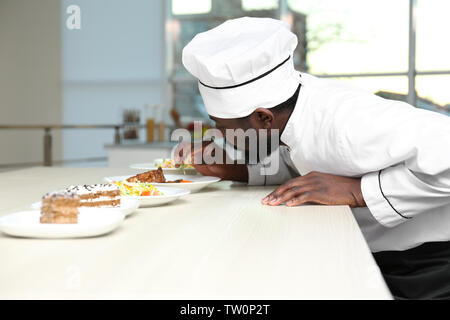 African American chef l'aggiunta di rosmarino di gustoso piatto in cucina Foto Stock