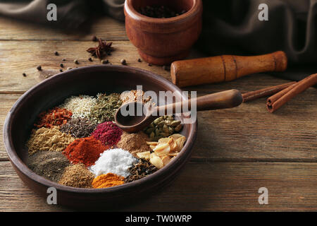 Piastra con spezie aromatiche sul tavolo di legno Foto Stock