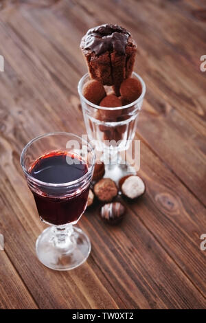 Bicchiere di vino rosso e dolci assortiti su sfondo di legno Foto Stock