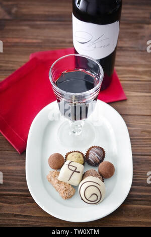 Vino Rosso e Cioccolatini assortiti su sfondo di legno Foto Stock