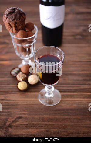 Vino rosso e dolci assortiti su sfondo di legno Foto Stock