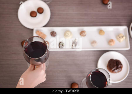 Femmina tenuta a mano bicchieri di vino rosso su un tavolo di legno Foto Stock