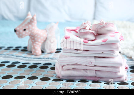 Pila di vestiti del bambino sul letto Foto Stock