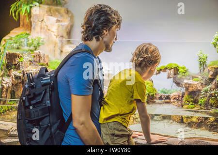 Padre e figlio guardando il pesce in un tunnel acquario Foto Stock