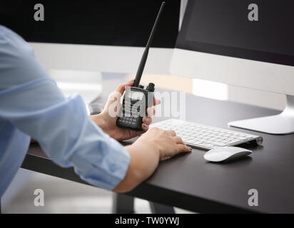 Femmina guardia di sicurezza tenendo la radio portatile in mano al lavoro Foto Stock