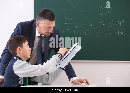 Insegnante maschio e schoolboy facendo attività in aula Foto Stock