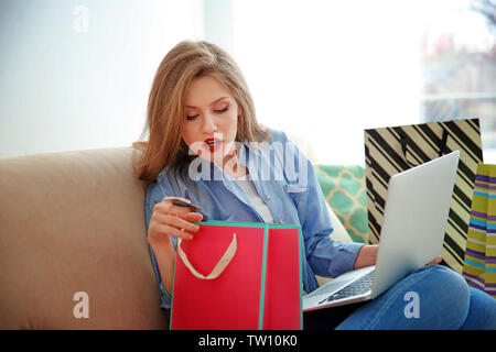 Bella giovane donna facendo shopping online a casa Foto Stock