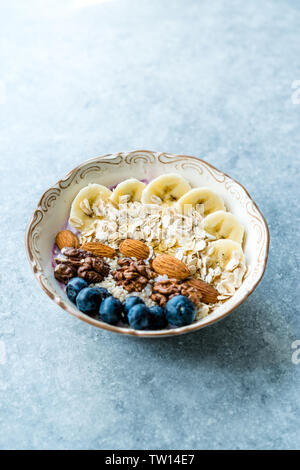 Acai ciotola con yogurt, Blackberry, fette di banana, noce, miele, marmellata, avena, mandorla, i semi di sesamo e granola in porcellana ciotola. Alimenti biologici. Foto Stock