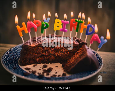 Buon compleanno torta al cioccolato con colorati candele accese Foto Stock