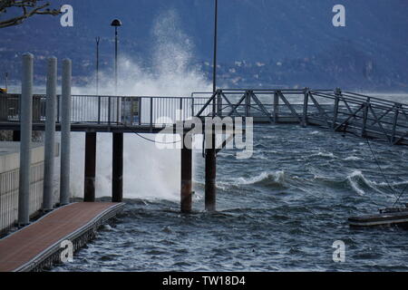 Alta ondata di schiantarsi su un molto ventoso giorno sul Lago Maggiore, Ticino su un molo Foto Stock