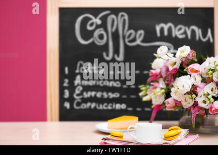 Tazza di caffè, gustosa torta e bouquet di fiori in cafe Foto Stock