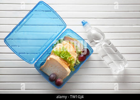 Lunchbox e bottiglia di acqua su sfondo di legno Foto Stock