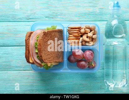Lunchbox e bottiglia di acqua su sfondo di legno Foto Stock