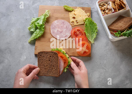 Donna che fa il gustoso panino sul tavolo Foto Stock