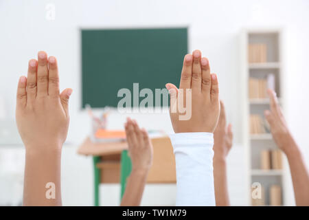 Bambini il sollevamento in alto le mani in aula Foto Stock