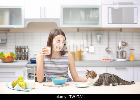 Mattina del giovane e bella donna e gatto in cucina Foto Stock