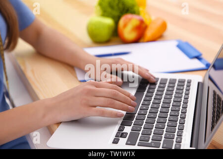 Giovani femmine nutrizionista lavora con il computer portatile in ufficio, primo piano Foto Stock