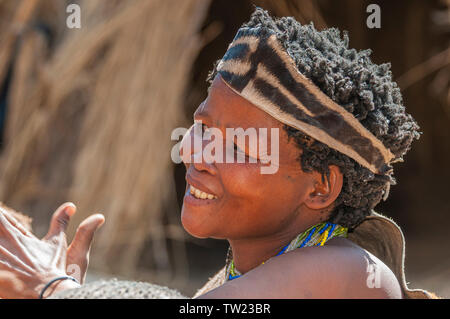 Un San donna, noto anche come i Boscimani, nella gioiosa umore, battendo le mani. Foto Stock