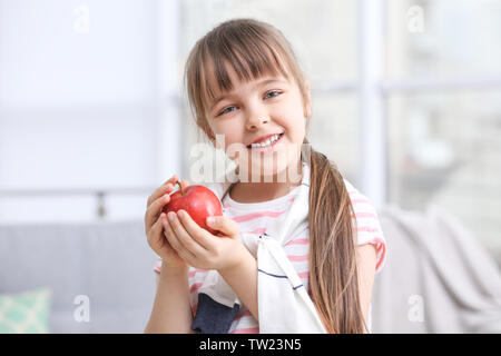 Felice schoolgirl in piedi con Apple da casa Foto Stock