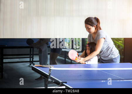 Asian madre e bambini coaching giocare a ping-pong gioco di sport d'estate vocazione. mom tenere figlia mano per utilizzare teble racchetta da tennis e la sfera è felice mo Foto Stock