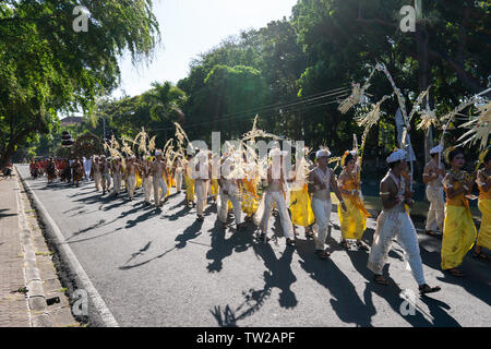 DENPASAR/BALI-Giugno 15 2019: Sampian ballerino, indossando giallo e bianco costume tradizionale, camminando per eseguire a Bali Arts Festival 2019. Essi utilizzano palm Foto Stock