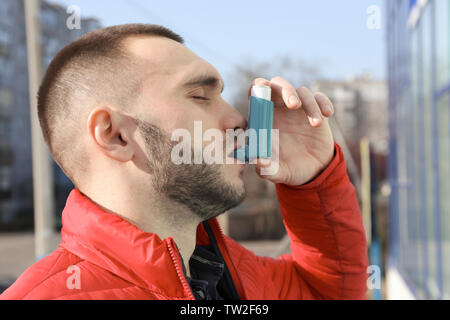 Giovane uomo utilizzando l'asma inalatore su strada Foto Stock