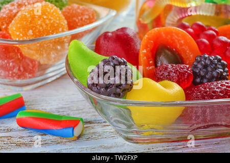 Vaso di vetro con gustosi jelly caramelle su sfondo di legno, primo piano Foto Stock