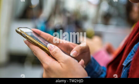 Asian tourist donna sedersi in metropolitana e mantiene lo smartphone. Passeggero utilizzando la tecnologia cellulare in metropolitana per il viaggio. Foto Stock