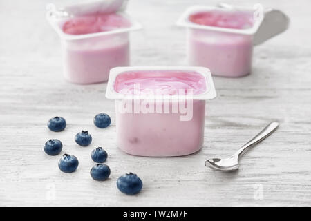 La coppa di plastica con yogurt e mirtilli sul tavolo di legno Foto Stock