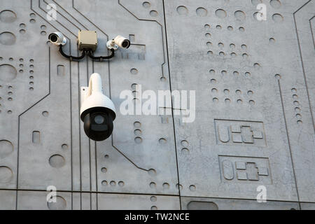 Tre esterni alle telecamere di sorveglianza bianco con il nero su grigio muro di cemento stilizzato di sfondo come chip di microcircuito Foto Stock