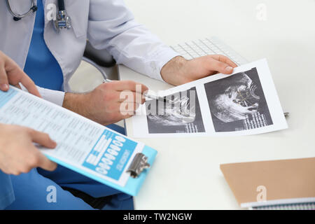 Medico e assistente medico discutendo sonogram immagine in office, primo piano Foto Stock