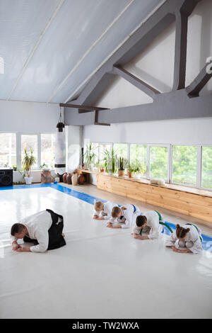 A partire aikido lezione. Bambini attivi e loro aikido trainer a partire aikido lezione nella spaziosa hall Foto Stock