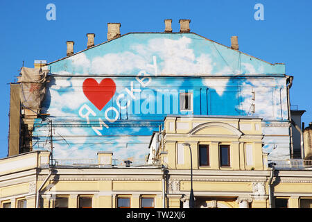 Iscrizione sul vecchio tetto di casa in russo "Io amo di Mosca", cuore rosso, cielo blu, il bianco delle nuvole, pareti di giallo pallido,aprire windows, camini, pluviali Foto Stock