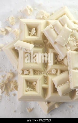 Bianco tagliato a pezzetti il cioccolato su uno sfondo chiaro in monichrome. Vista dall'alto. Foto Stock