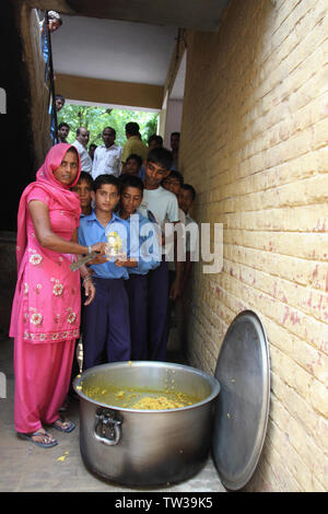 Anganwadi lavoratore che dà cibo a studente, India Foto Stock