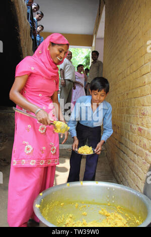 Anganwadi lavoratore che dà cibo a studente, India Foto Stock