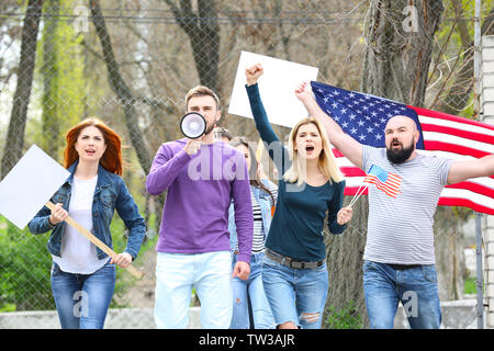 Gruppo di protesta dei giovani con la bandiera americana sulla strada Foto Stock