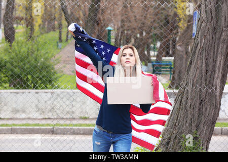 Protestando giovane donna holding pezzo di cartone con spazio per il testo e la bandiera americana sulla strada Foto Stock