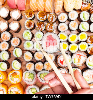 Vista dall'alto di bastoncini con tonno nori roll over set di sushi e rotola sul tavolo di legno Foto Stock