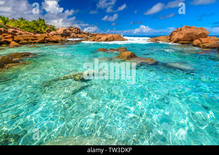 Il mare turchese della piscina naturale di La Digue. Cancellare le acque calme di piscine ad Anse Cocos vicino a Grand Anse e Petite Anse protetto da roccia Foto Stock