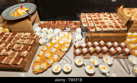 Piccola pasticceria assortita schierate decorata su dessert a buffet lungo con insalata di frutta. Sweet paradise. Foto Stock