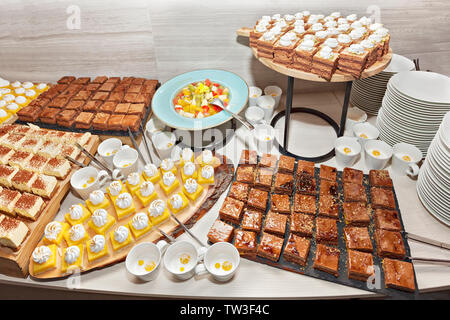Piccola pasticceria assortita schierate decorata su dessert a buffet lungo con insalata di frutta. Sweet paradise. Foto Stock