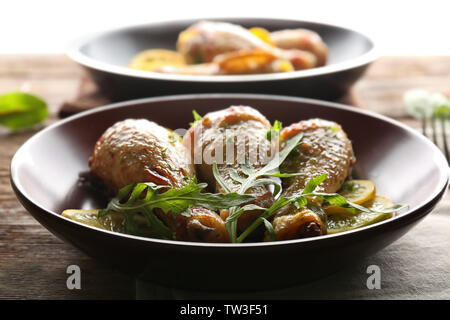 Piastra con delizioso pollo arrosto cosce di pollo disossate e fette di limone su un tavolo di legno Foto Stock