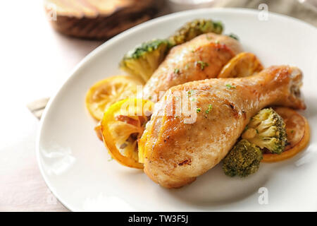 Delizioso pollo arrosto bacchette con spicchi di limone sulla piastra Foto Stock