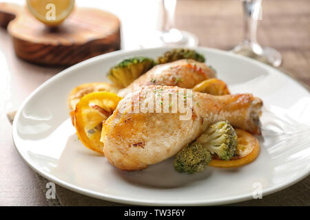 Piastra con delizioso pollo arrosto cosce di pollo disossate e limone sul tavolo Foto Stock