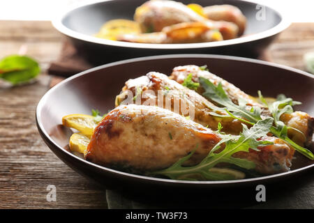 Piastra con delizioso pollo arrosto cosce di pollo disossate e fette di limone su un tavolo di legno Foto Stock