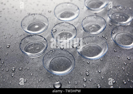 Le lenti a contatto e gocce di acqua su sfondo grigio Foto Stock